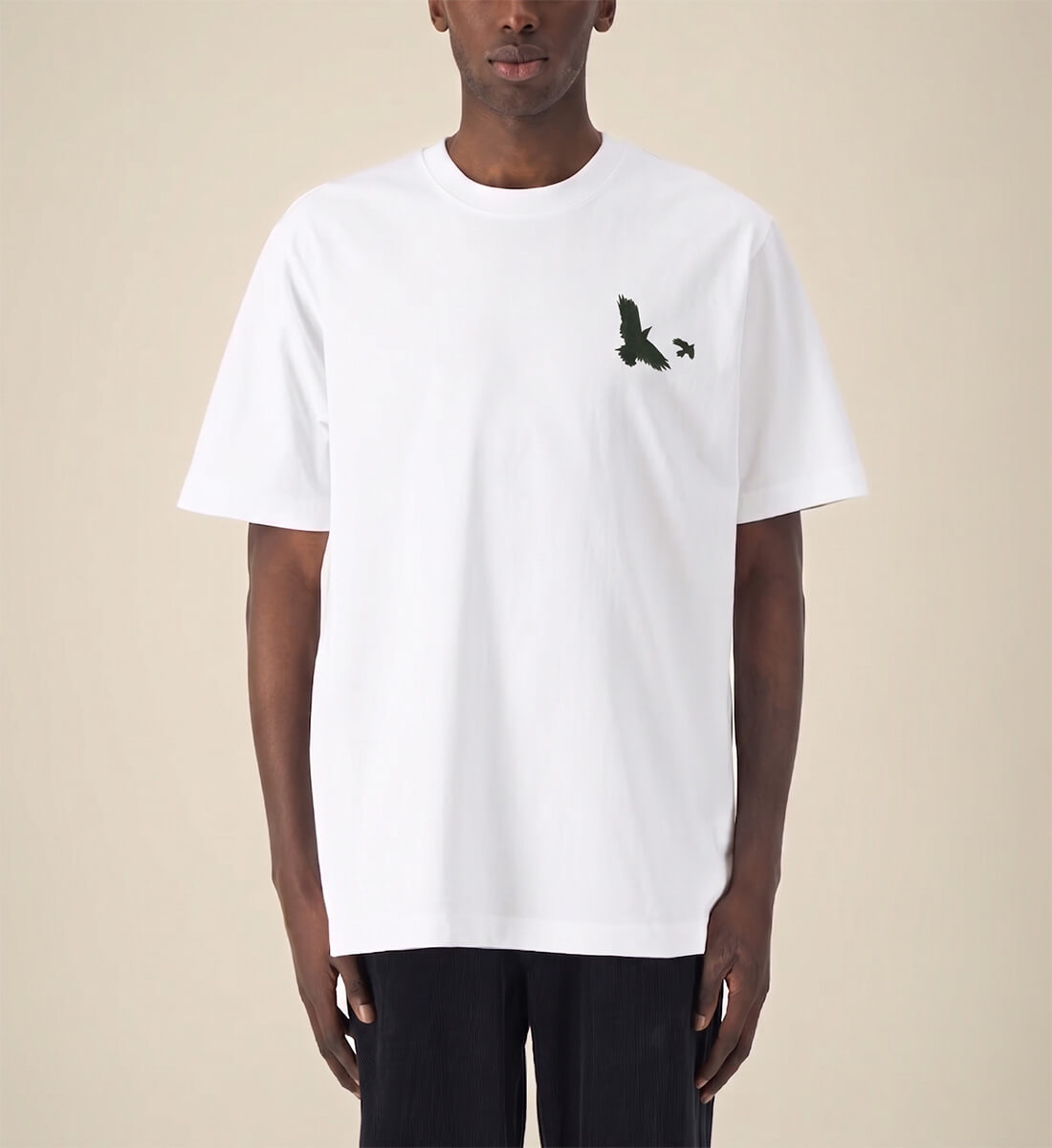 Mann trägt Unisex Oversized Streetwear T-Shirt in Weiß, minimalistische schwarze Krähe als kleiner Brustprint, Mugen no Karasu