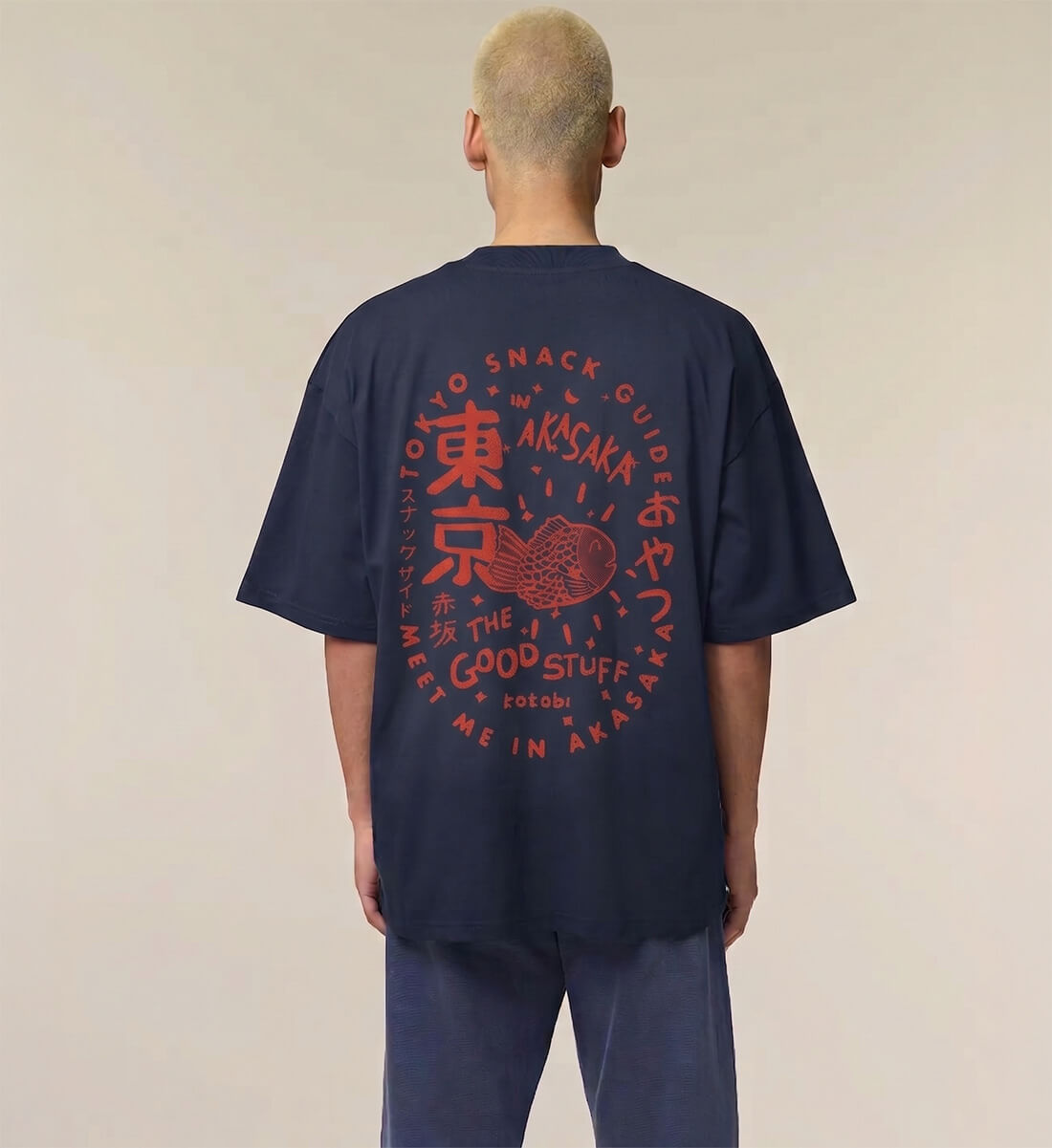 Rückseite eines dunkelblauen T-Shirts mit großem rotem, kreisförmigem Backprint. Das Design zeigt ein Taiyaki-Gebäck, umrahmt von den Texten "TOKYO SNACK GUIDE", "MEET ME IN AKASAKA", "THE GOOD STUFF" sowie japanischen Schriftzeichen.