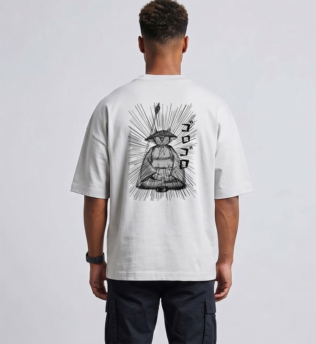 Ein Mann von hinten trägt ein hellgraues Oversized T-Shirt (Bio-Baumwolle) von totobi. Auf dem Rücken ist eine große, handgezeichnete Grafik einer meditierenden Katze in traditioneller Mönchskleidung mit dynamischen Manga-Aktionslinien und japanischen Schriftzeichen abgedruckt.
